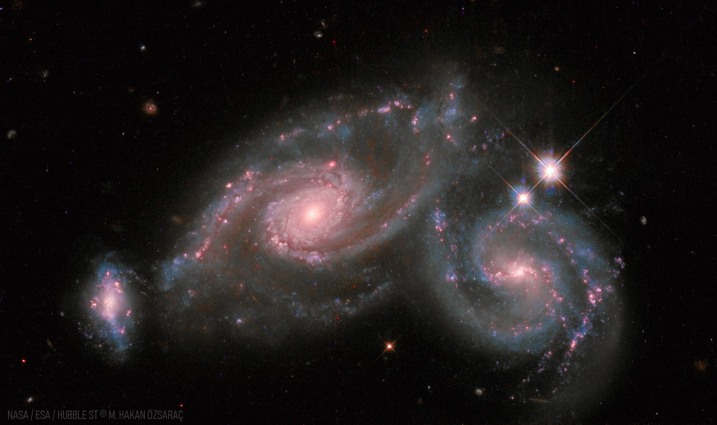 Lorsque deux galaxies entrent en collision, ce n’est généralement pas le cas des étoiles qui les composent. En effet, les galaxies sont pour la plupart des espaces vides et, aussi brillantes soient-elles, les étoiles n’occupent qu’une petite fraction de cet espace. Mais lors de la collision, une galaxie peut déchirer l’autre gravitationnellement, et la poussière et le gaz communs aux deux galaxies entrent en collision. Si les deux galaxies fusionnent, les trous noirs qui résidaient probablement au centre de chaque galaxie pourraient éventuellement fusionner. Parce que les distances sont si grandes, tout se déroule au ralenti – sur des centaines de millions d’années. Outre les deux grandes galaxies spirales, une troisième galaxie plus petite est visible à l'extrême gauche de l'image présentée d'Arp 274, également connue sous le nom de NGC 5679. Arp 274 s'étend sur environ 200 000 années-lumière et se trouve à environ 400 millions d'années-lumière en direction de la constellation de la Vierge. © Nasa, ESA, Hubble ; Traitement et droits d'auteur : Mehmet Hakan Özsaraç